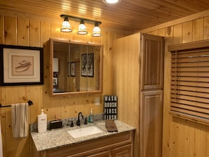 Ein Badezimmer aus Holz mit Waschbecken, Spiegel und drei Pendelleuchten.