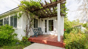 Une maison blanche avec un porche, une pergola en bois et le numéro « 1935 » sur la porte.