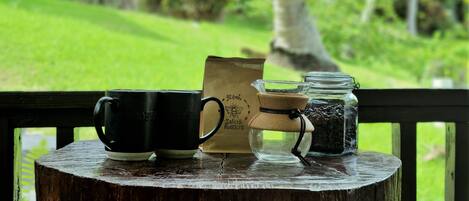 A rustic wooden table with two black mugs, a paper bag labeled "Salisch Roasters," and a glass jar with coffee beans.