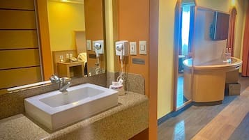 A hotel bathroom with a large sink, a mirror, and a hairdryer.