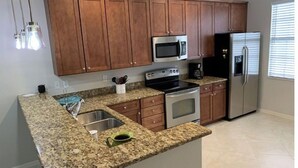 Una cocina con encimeras de granito, electrodomésticos de acero inoxidable, armarios de madera y microondas integrado.