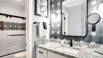Une salle de bain moderne avec des toilettes blanches, un lavabo doté d’un plan de travail en marbre et un grand miroir.