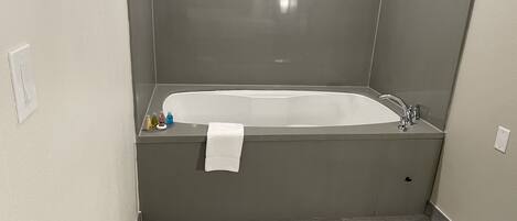 Un baño con bañera, una toalla y artículos de aseo.