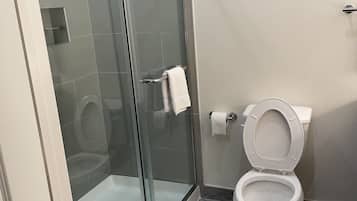 Une salle de bain moderne avec une douche à parois de verre, des toilettes et un sol en marbre.