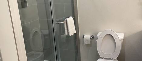 Un baño moderno con ducha de vidrio, inodoro y piso de mármol.