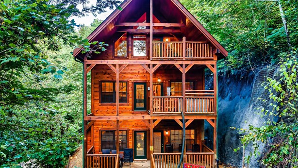 Una cabaña de madera con balcón, un porche y una pequeña zona de estar al aire libre.