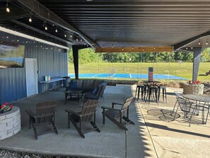Een terras buiten met een overdekte zithoek, een zwembad en uitzicht op het omliggende landschap.