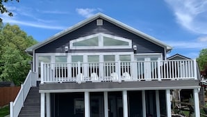 Une maison à deux étages avec un balcon, une véranda à l’avant et une allée.