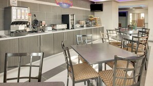 A breakfast area with a counter, coffee machines, and seating. - Baymont by Wyndham Terrell (Terrell)