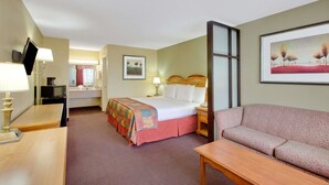 A hotel room with a bed, a desk, a chair, a sofa, a TV, a painting, and a window. - Baymont by Wyndham Terrell (Terrell)