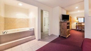 A modern bathroom with a large bathtub, a shower area, and a television on a wooden cabinet. - Rodeway Inn Decatur (Decatur)