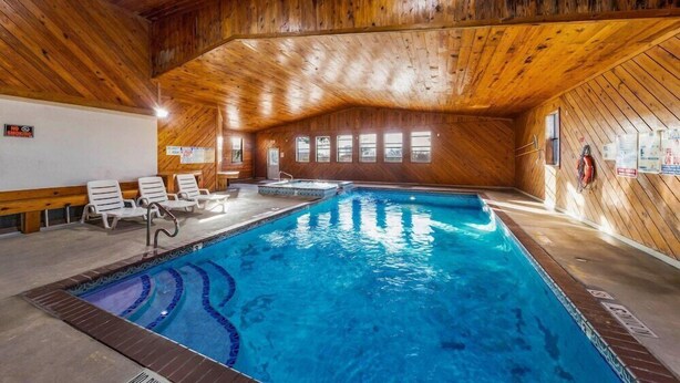 An indoor swimming pool with wooden walls and ceiling, clear blue water, and several lounge chairs. - Rodeway Inn Decatur (Decatur)