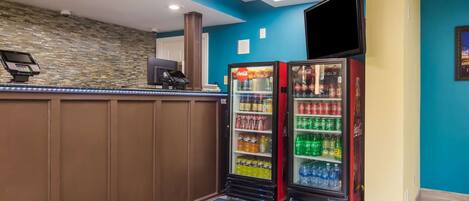 Uma área de recepção com balcão, parede de pedra e dois refrigeradores de Coca-Cola.