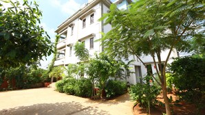 A multi-story building with a garden area in front. - Hotel Du Palais (Vanur)