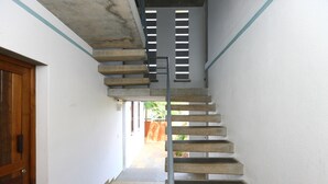 A concrete staircase with metal railings, leading to an outdoor area with a view of greenery. - Hotel Du Palais (Vanur)