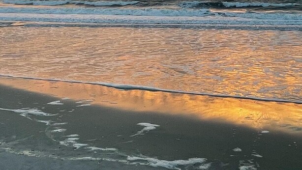 Una playa con olas y un cielo al atardecer.