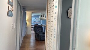 Un corridoio stretto con pavimento in legno, una sedia nera e una porta con pannello decorativo.