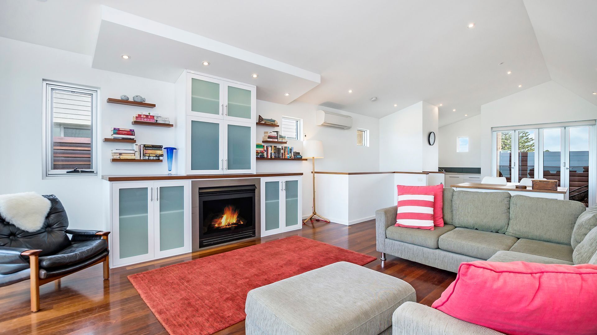 Una sala de estar moderna con chimenea, un sofá, una mesa de centro y un comedor con vistas.