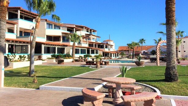 A resort with multiple-story buildings, a swimming pool, and outdoor seating areas.