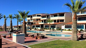 A resort with a swimming pool, palm trees, and outdoor seating areas.