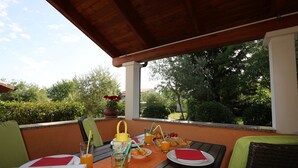 An outdoor dining area with a table set for two, featuring a beverage dispenser, plates, and cutlery. - Vacation apartment Bungalow Melisa 5 with pool (POREC)