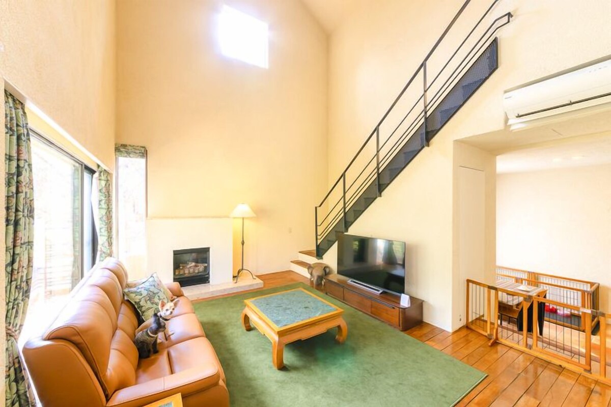A spacious living room with a sofa, a coffee table, a TV, and a staircase.