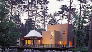 A modern house with a deck overlooking a pond, surrounded by trees. - Forest Village (Fujikawaguchiko)