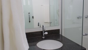 A modern bathroom with a glass shower enclosure, a round sink, and a large mirror. - Hotel Alphaville (Ouvidor)
