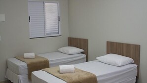 A hotel room with three single beds, a window with blinds, an air conditioning unit, and a ceiling light. - Hotel Alphaville (Ouvidor)