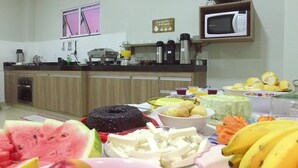 A kitchen with wooden cabinets, a microwave, and various fruits and vegetables on the counter. - Hotel Alphaville (Ouvidor)