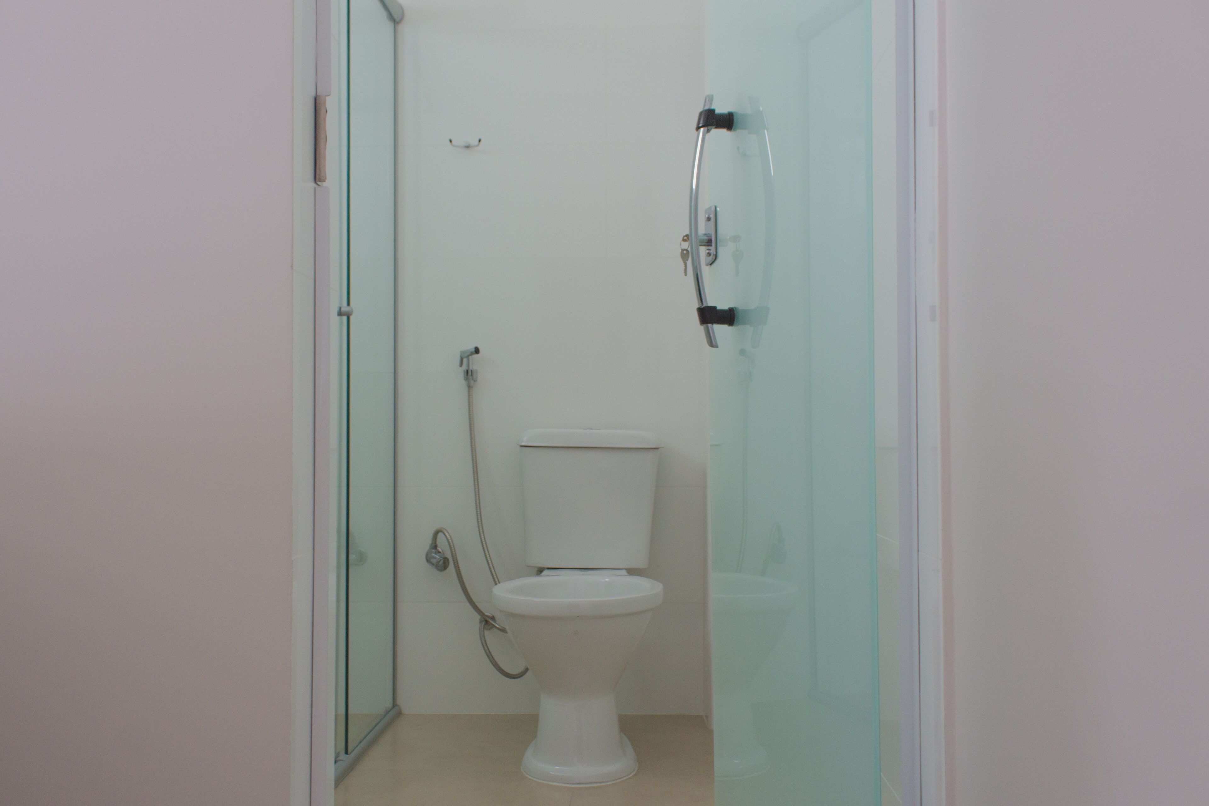 Un baño pequeño y moderno con cabina de ducha de vidrio, inodoro blanco y puerta de vidrio.
