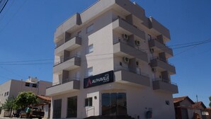 A multi-story hotel with balconies, a sign reading "Alphaville Hotel," and a clear blue sky in the background. - Hotel Alphaville (Ouvidor)