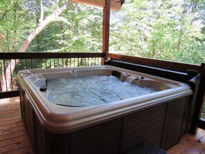 Un bain à remous sur une terrasse en bois, avec vue sur les arbres.