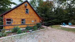 A rustic log cabin with a porch, a gravel pathway, and outdoor seating.