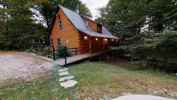 A log cabin with a porch, surrounded by trees. - Serendipitous Luxury Cabin with Forest Views, Hot Tub, mins from Hocking Hills (Logan)