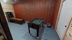 A room with a foosball table, a pool table, and a brick wall. - Serendipitous Luxury Cabin with Forest Views, Hot Tub, mins from Hocking Hills (Logan)