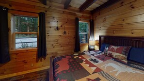 A wooden cabin room with a bed, two windows, and a nightstand. - Serendipitous Luxury Cabin with Forest Views, Hot Tub, mins from Hocking Hills (Logan)