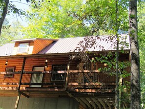 Une cabane rustique avec une façade en bois, un toit en métal et un balcon doté de balustrades.