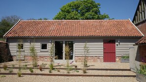 A single-story building with a red-tiled roof, a red door, and a small window. - The Cartlodge near Woodbridge - recently converted barn (Woodbridge)