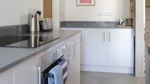 A modern kitchen with white cabinets, a stainless steel range hood, and a countertop with a kettle and toaster. - The Cartlodge near Woodbridge - recently converted barn (Woodbridge)