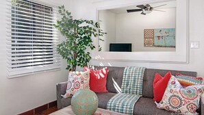 A living room with a grey sofa, patterned cushions, a large vase, and a ceiling fan. - Air Concierge Old Town Charming Cottages 1 (San Diego)