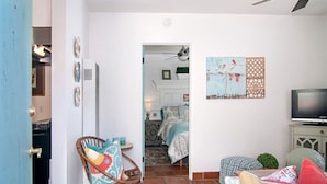 A room with a bed, a television, and a chair with cushions. - Air Concierge Old Town Charming Cottages 1 (San Diego)