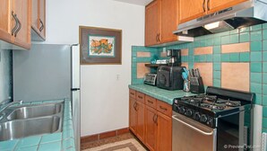 A kitchen with wooden cabinets, a gas stove, a microwave, and a sink. - Air Concierge Old Town Charming Cottages 1 (San Diego)