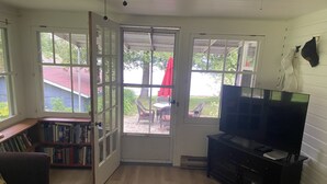Un salon équipé d’un téléviseur, d’une bibliothèque et d’une porte donnant sur une terrasse.