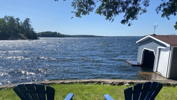 Deux fauteuils Adirondack sont placés face à un lac, avec un quai et un abri de jardin.
