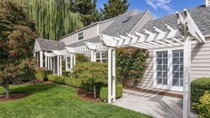 A residential house with a covered porch and a well-maintained lawn. - Charming home with pet-friendly garden space and new hot tub! (Eugene)