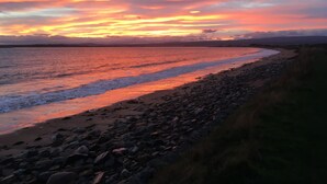 A beach with a rocky shoreline and a sunset in the background. - Seaside cottage by a sandy beach - dolphins, golf, near Inverness and Loch Ness (Rosemarkie)