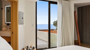 Une chambre dotée d’une grande porte-fenêtre coulissante donnant sur un balcon avec vue sur la mer.