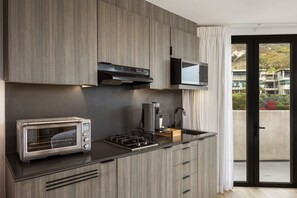 Cozinha moderna com micro-ondas embutido, torradeira e máquina de café, e porta de vidro deslizante para uma varanda.