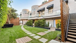 Un bâtiment moderne à plusieurs étages, doté d’une cour intérieure, d’une terrasse en bois et de plantes en pot.